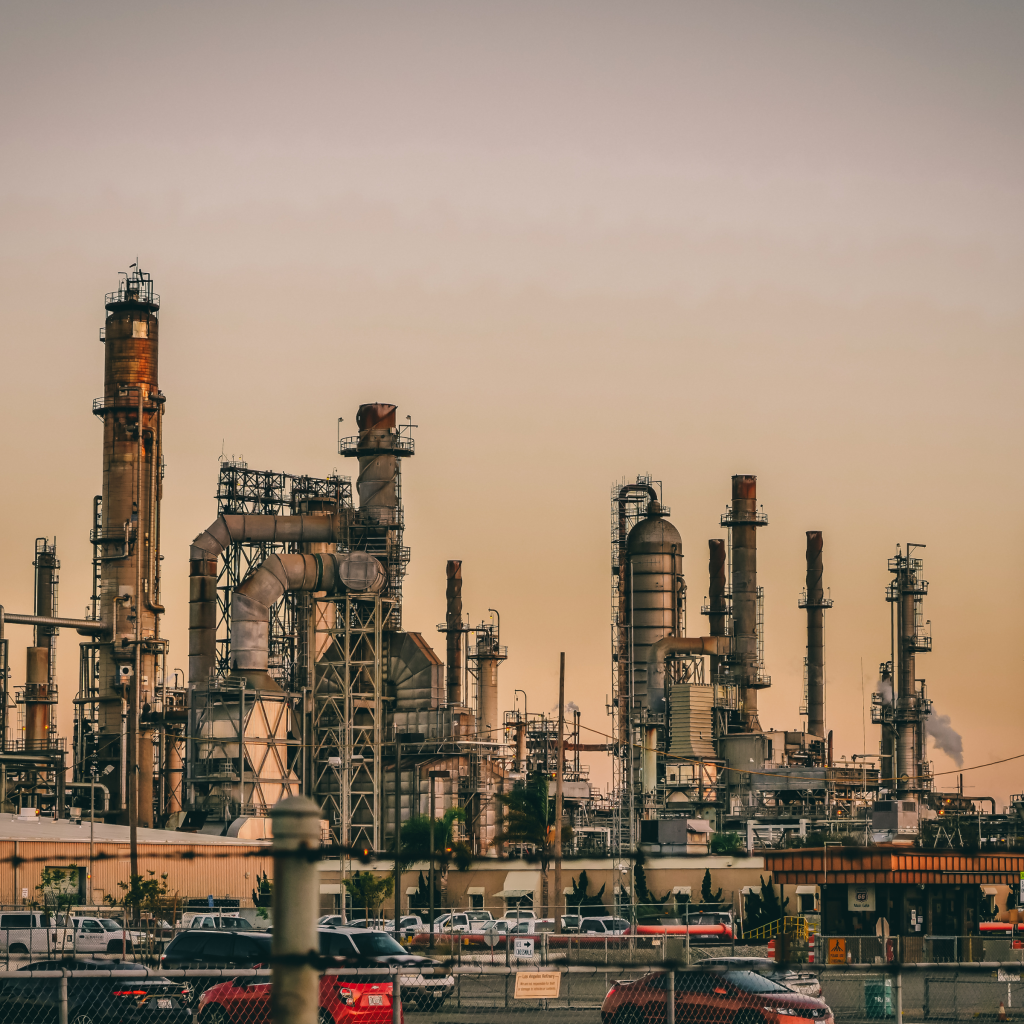 Industrial facility with pipes and chimneys at sunset.