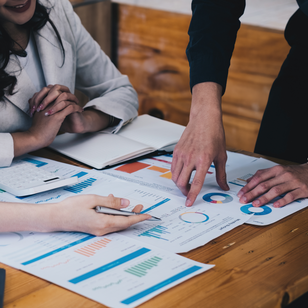 People reviewing business charts and reports on a table.