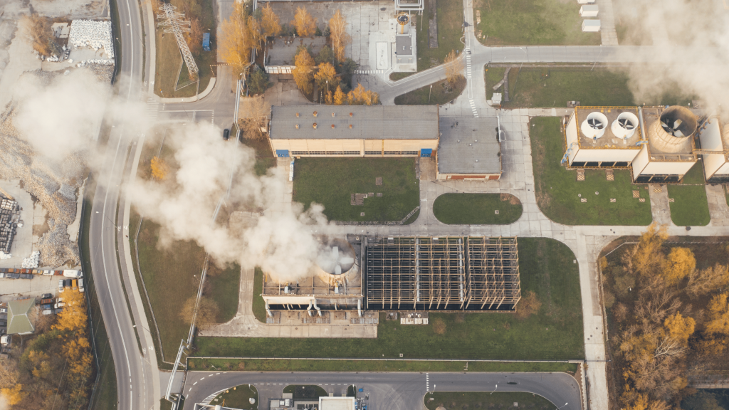 Aerial view of industrial facility with smoke emissions representing carbon accounting in sustainability consulting.